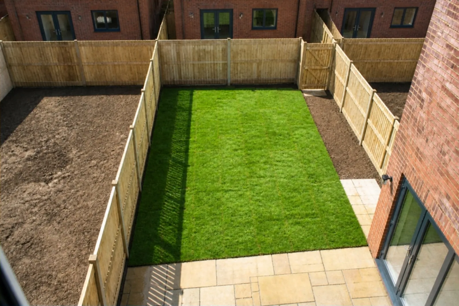 A freshly turfed narrow new-build garden seen from an upstairs window
